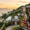 海と巨大な橋を一望する高台の温泉リゾートと夕日を眺めるカップル